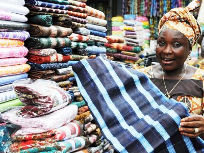 Adenike Akinlosose, 48, a dealer in African textiles, shows her fabrics at Balogun market in Lagos October 24, 2011. The United Nations says the world population will hit seven billion near the end of October. UN Secretary-General Ban Ki-moon will announce the milestone, and issue a call to action to world leaders to meet the challenges that a growing population poses. AFP PHOTO / PIUS UTOMI EKPEI (Photo credit should read PIUS UTOMI EKPEI/AFP/Getty Images)